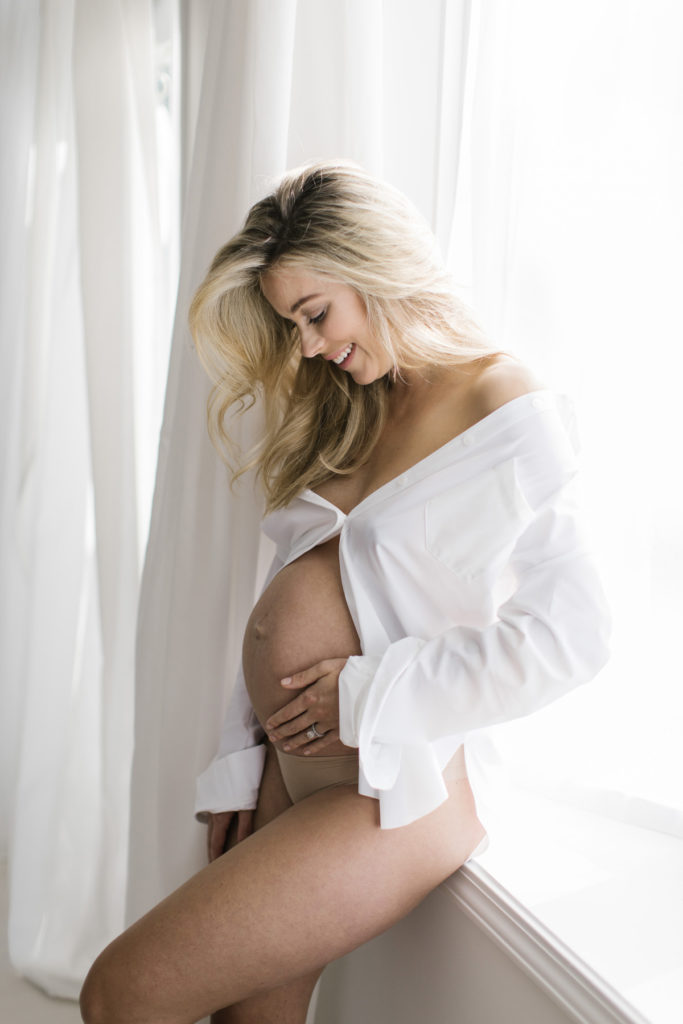 woman looking down at her belly during pregnancy session
