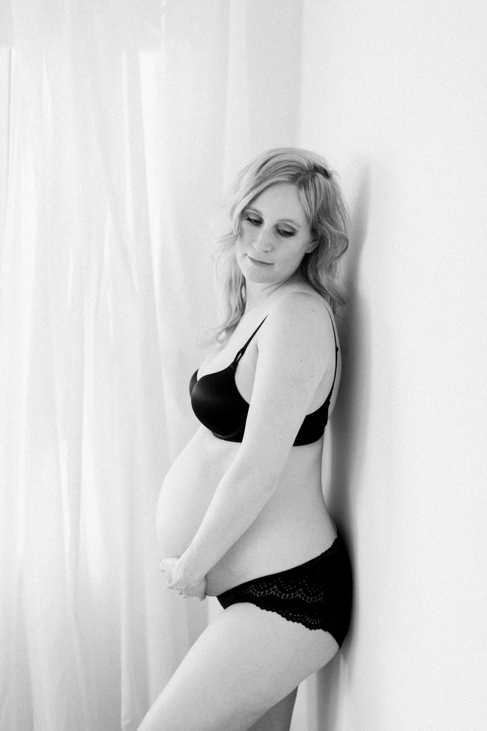 black and white image of woman holding belly with black lingerie