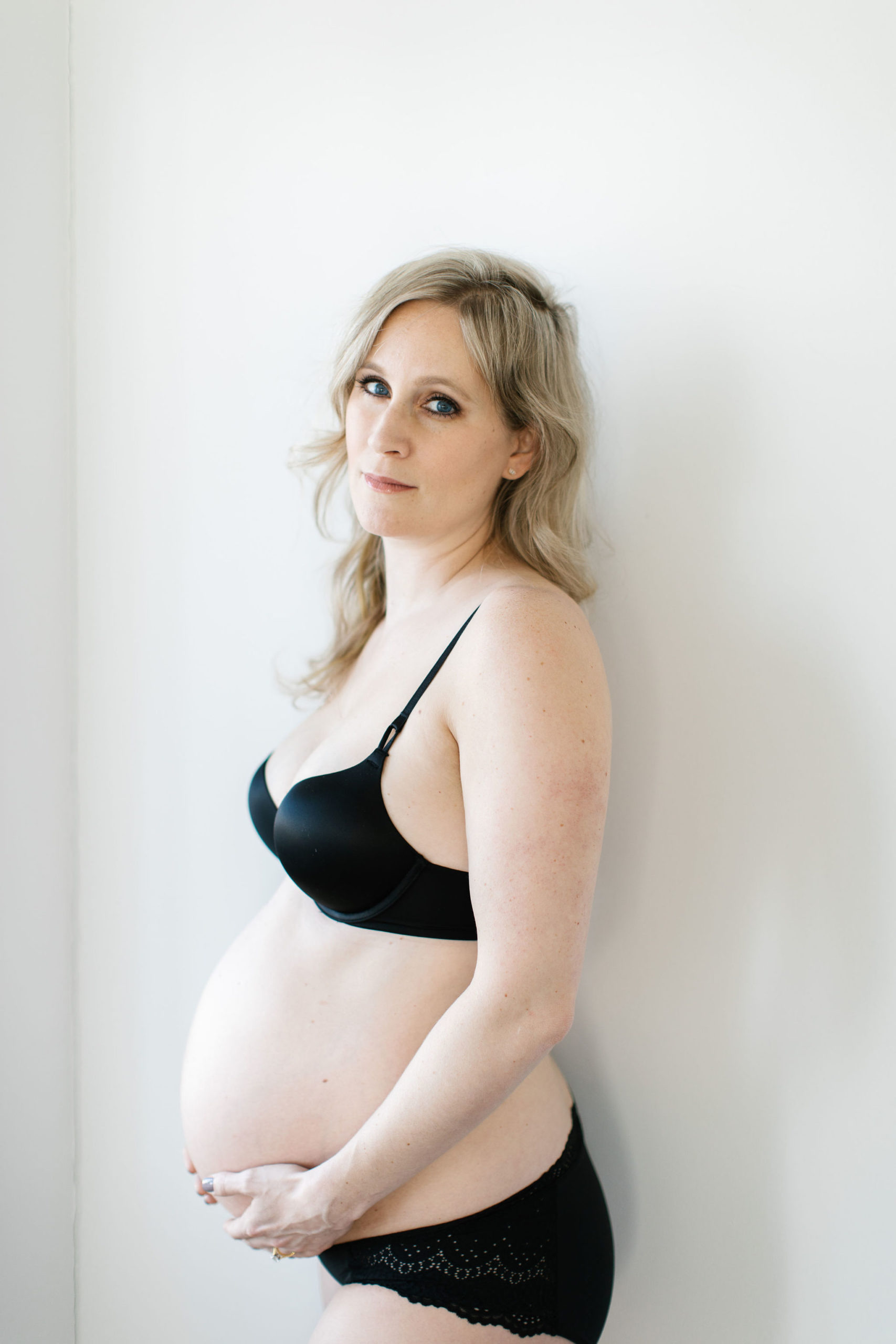 blonde woman holding belly during maternity session and a unique time of my life