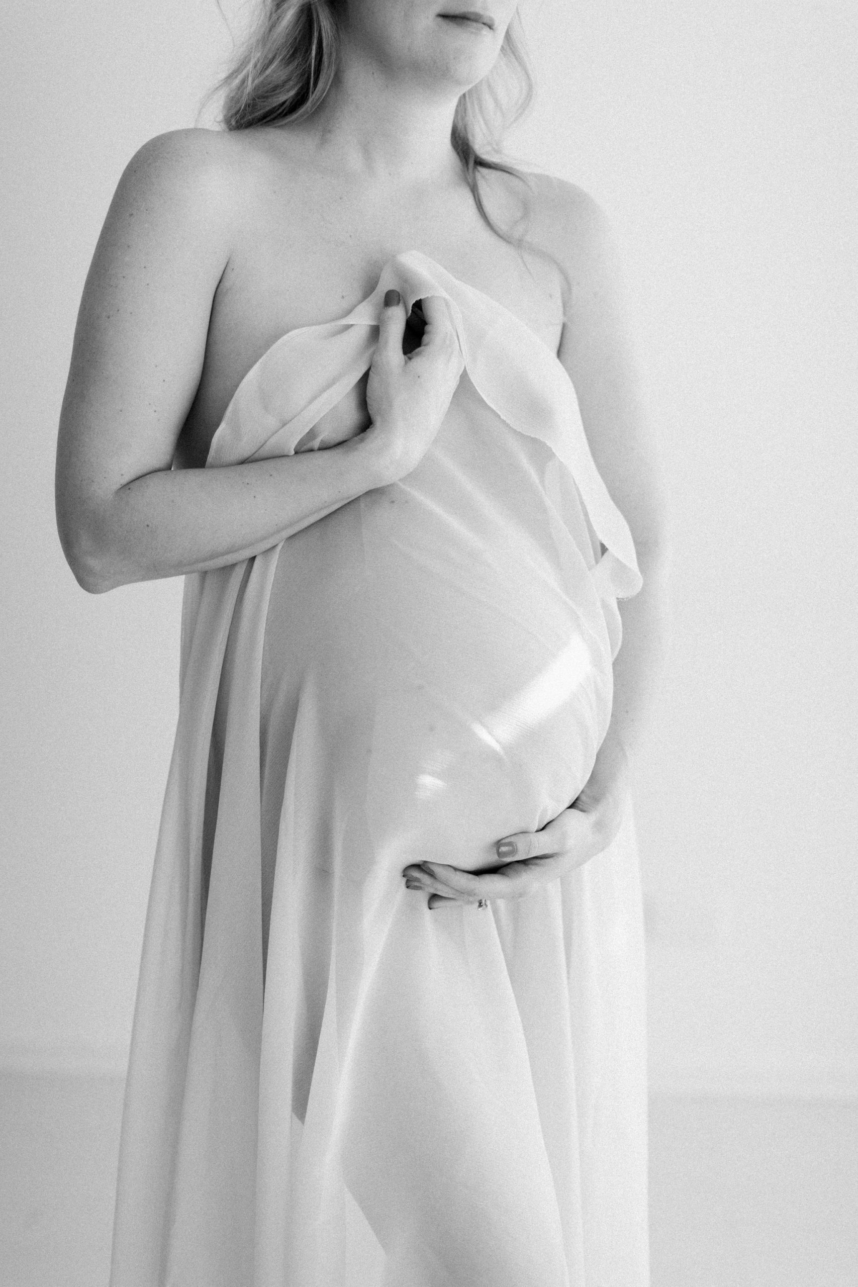 black and white image of a woman holding her belly during pregnancy session